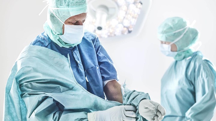Kirurgi pukeutuu leikkaustakkiin ennen leikkausta