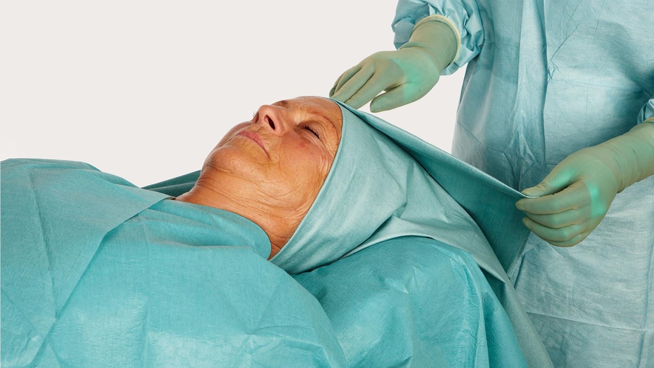 potilaan pää knk-leikkauslakanalla peiteltynä